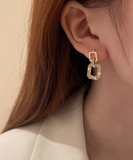 Model wearing geometric gold drop earrings