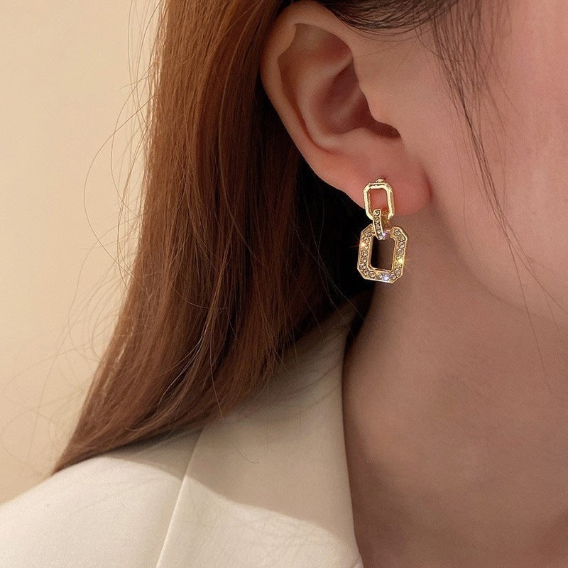 Model wearing geometric gold drop earrings