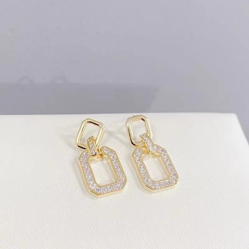 Close-up of geometric gold drop earrings, pavé detail