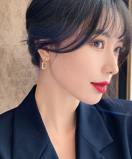 Close-up of a person wearing a gold earring with a neutral background