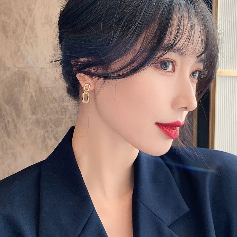 Close-up of a person wearing a gold earring with a neutral background