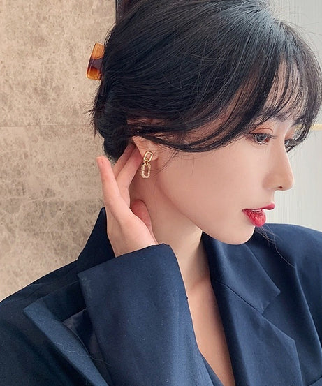 Woman wearing a gold earring with a neutral background