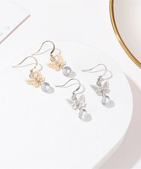 Butterfly crystal drop earrings in gold and silver on white tray
