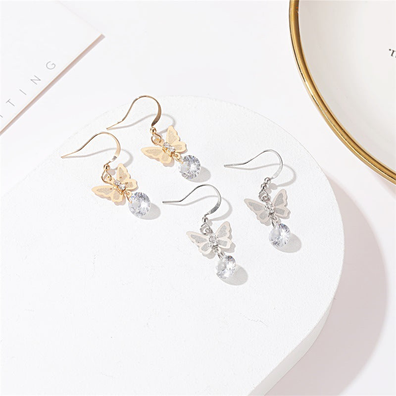 Butterfly crystal drop earrings in gold and silver on white tray