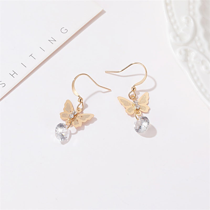Butterfly crystal drop earrings in gold on white tray