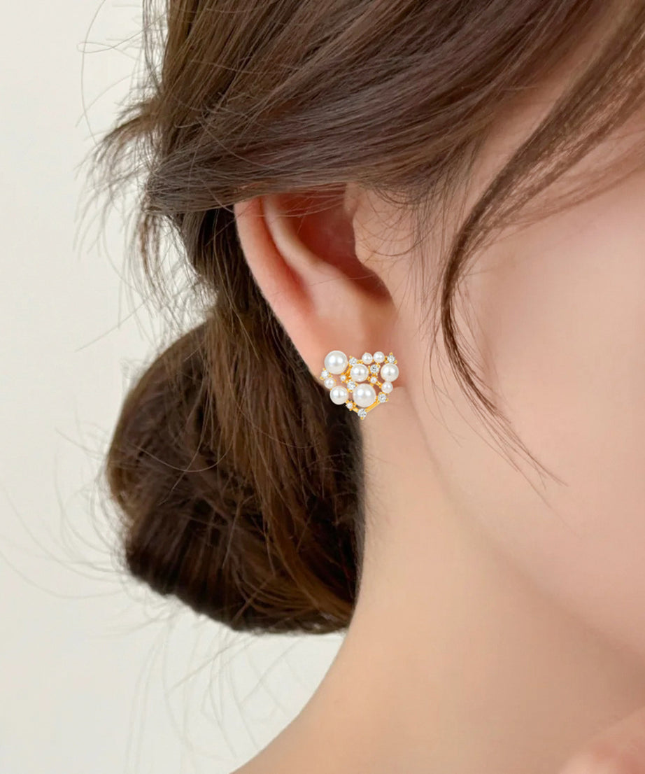 Close-up of an ear wearing a pearl earring with a neutral background