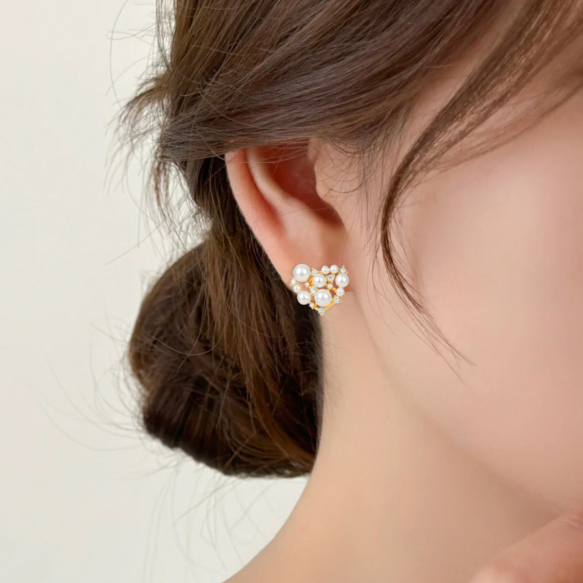 Close-up of an ear wearing a pearl earring with a neutral background