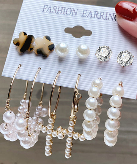 Detail of gold hoop earrings with pearl accents.