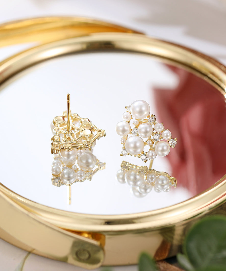 Pair of pearl earrings on a gold compact mirror with a blurred background