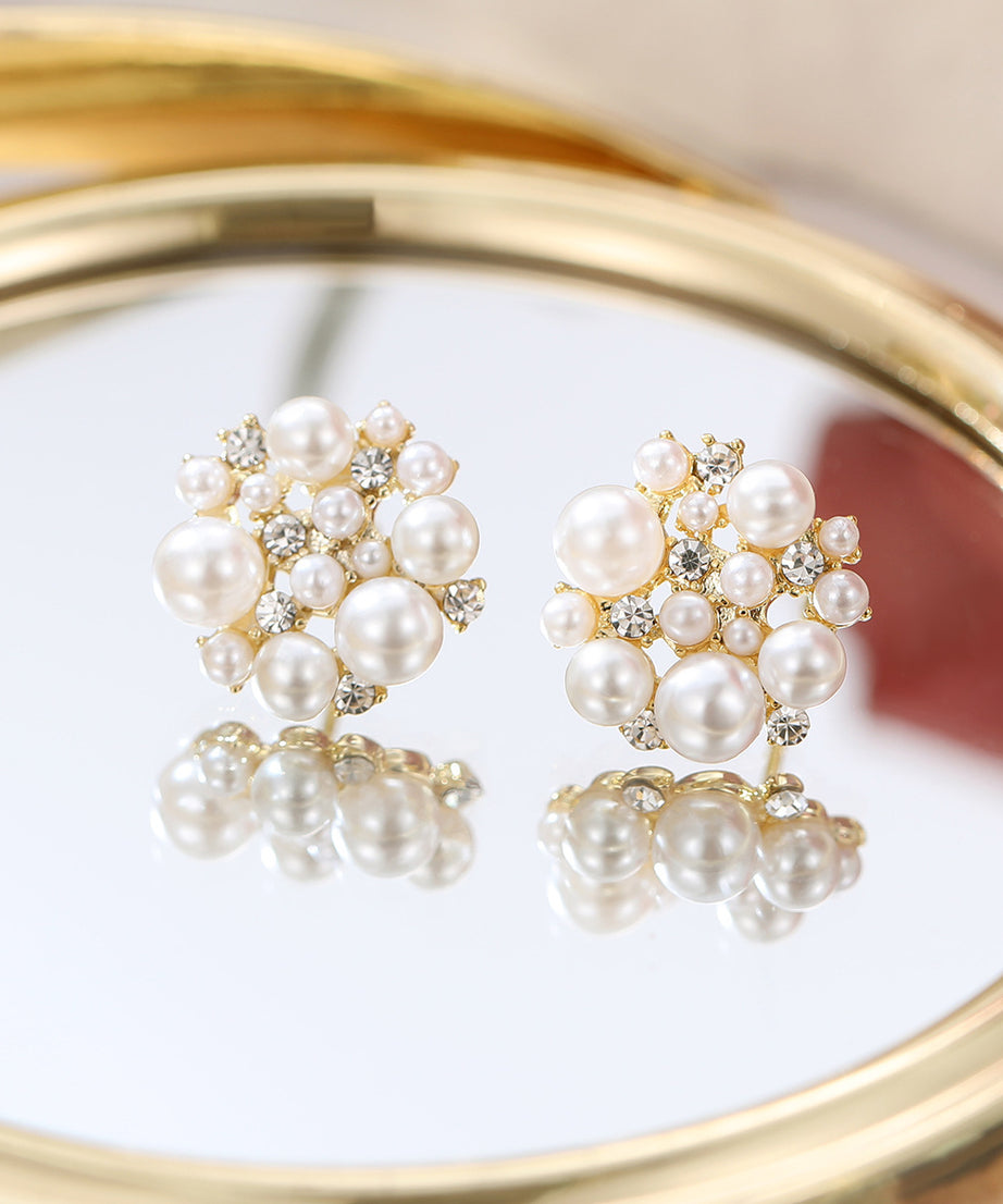 Pearl earrings with gold accents on a reflective surface