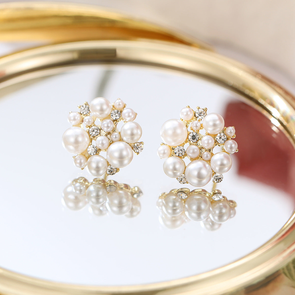 Pearl earrings with gold accents on a reflective surface