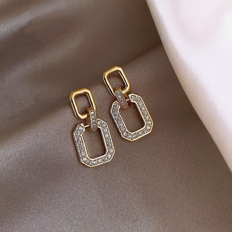 Gold and diamond earrings on a brown fabric background